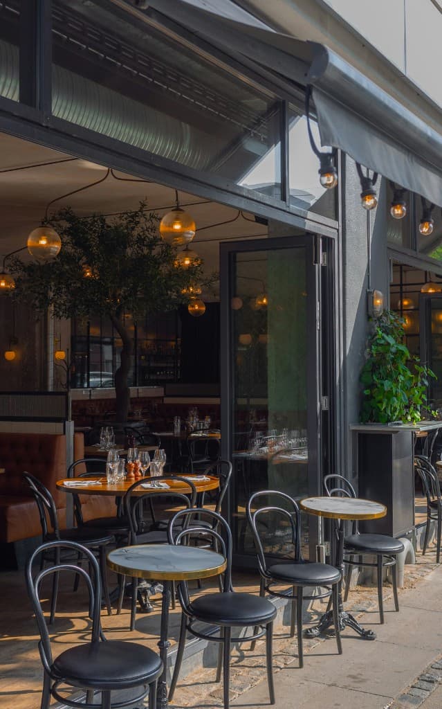 Modern restaurant exterior with large glass storefront windows and outdoor patio seating